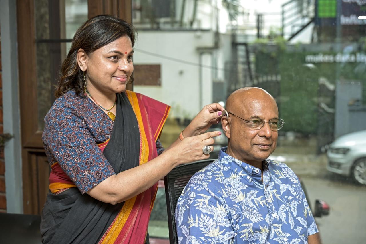 Audiologist fitting an invisible hearing aid for an Indian woman in a modern hearing clinic